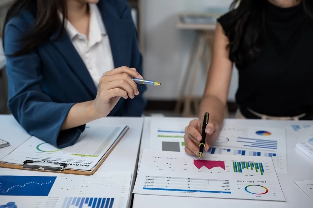 Two people reviewing content and charts together at a desk