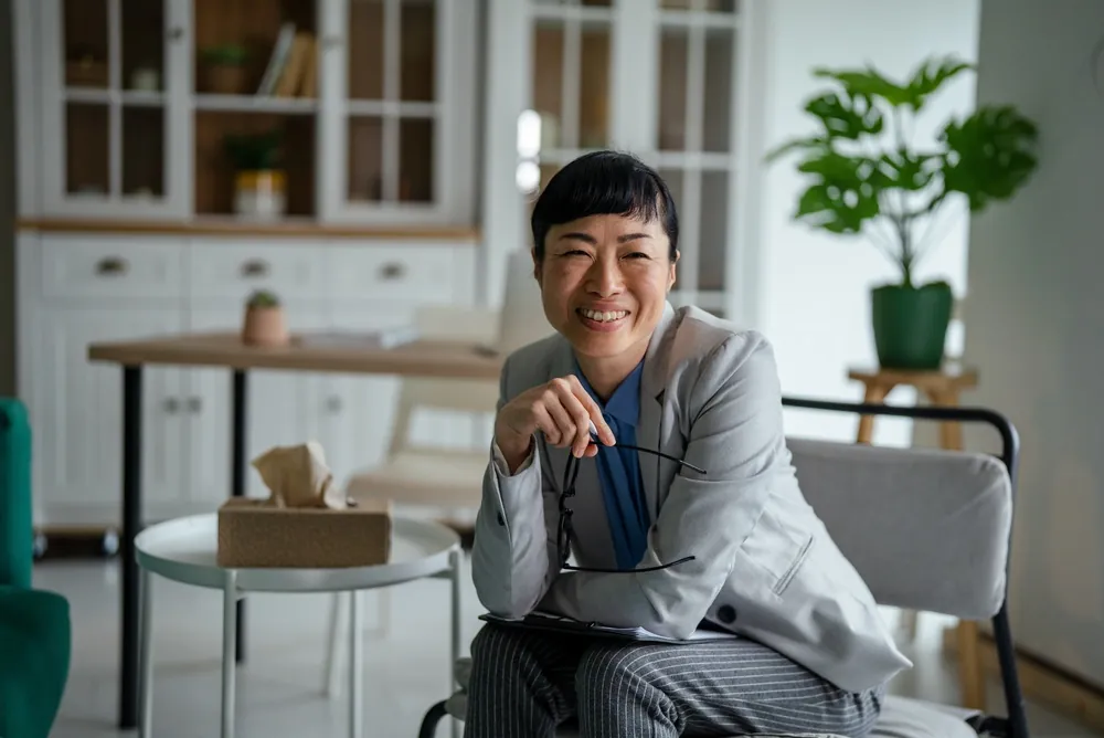 Business owner smiling, holding her glasses, ready to talk through a deal